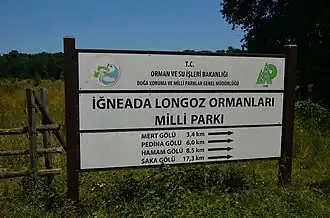 Знак на входе в национальный парк Пойменные леса Игнеады. Внизу — направление и расстояние до заповедника Озеро Сака