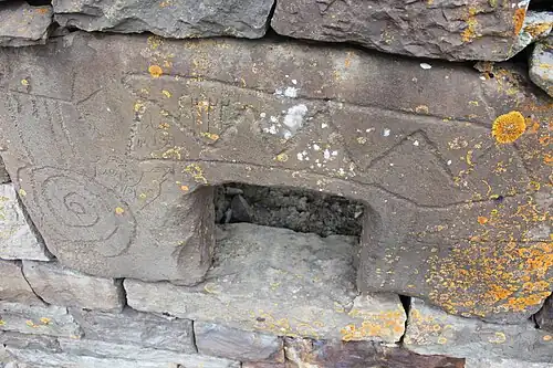 Арочный камень, видны древние петроглифы и более поздние арабские цифры.