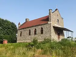 Каменный костёл с красной крышей и арочными окнами в селе Городнявка, Украина.