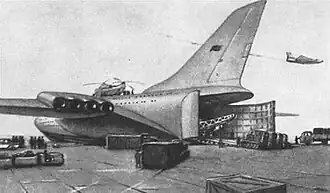 Океанский лайнер стоит в порту с открытым грузовым люком и принимает на борт грузовики и гусеничную технику (эскиз)