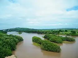 Река Раздольная у села Утёсное, вид с моста вниз по течению.Устье Комаровки слева, примерно в 1 км ниже по течению.Вдали — Хенина сопка (г. Уссурийск)