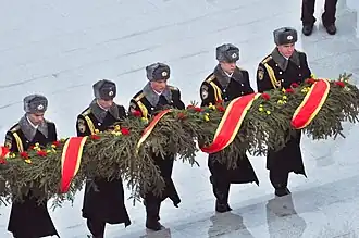 Солдаты президентского полка возлагают к подножию Стелы еловую гирлянду, которую привезли на площадь танкисты