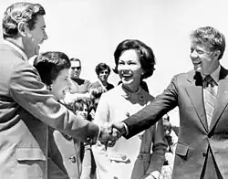 Carter shaking hands with Reubin Askew, with Carter’s wife smiling while standing in the middle of them
