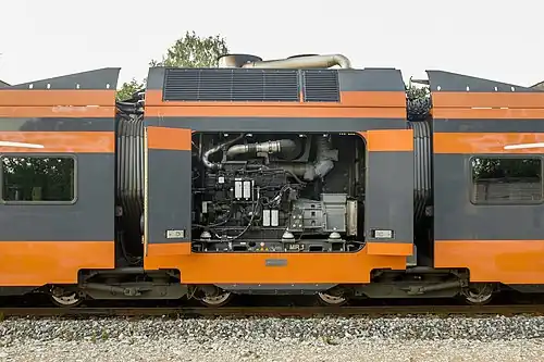 Промежуточный сочленённый дизель-генераторный модуль дизель-поезда Stadler Flirt с открытыми дверцами моторного отсека. При этом тяговые двигатели расположены в соседних пассажирских вагонах